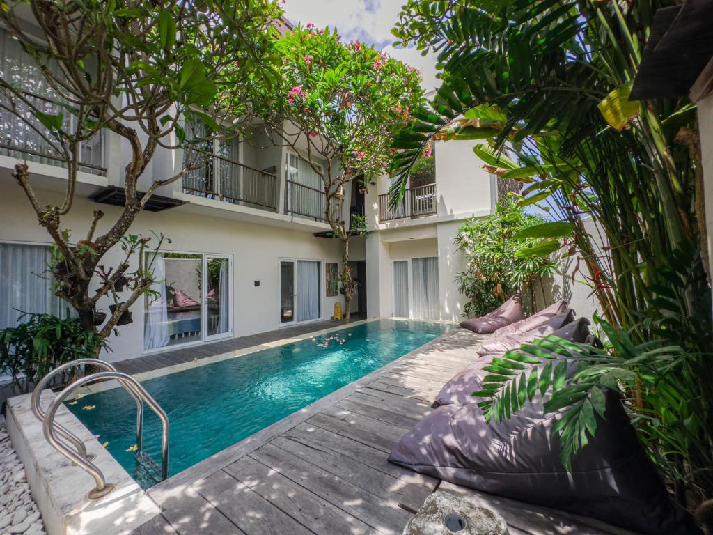 uma piscina em frente a um edifício com árvores em Hola Seminyak em Seminyak