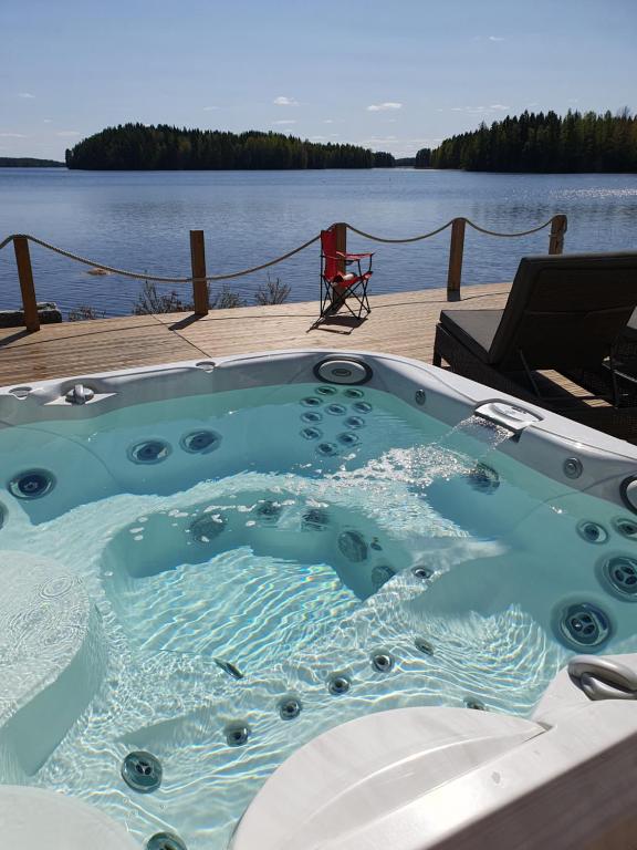 a jacuzzi tub sitting next to a body of water at Stunning log cabin 45m2 on the shore of Kallavesi. in Kuopio