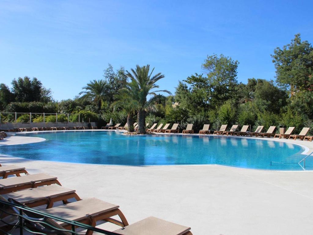 une grande piscine avec des chaises longues et des arbres dans l'établissement Charmant T2 climatisé avec terrasse et piscine, proche plages et commerces - FR-1-768-5, aux Issambres