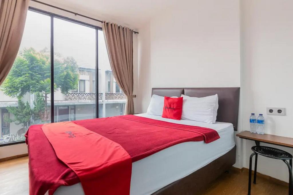a bedroom with a bed with a red blanket and a window at RedDoorz Plus near ICE BSD 2 in Tangerang