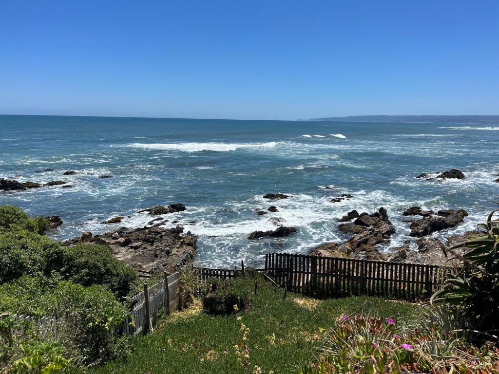 a view of the ocean with a fence and rocks at Inigualable vista frente al mar in Pichilemu