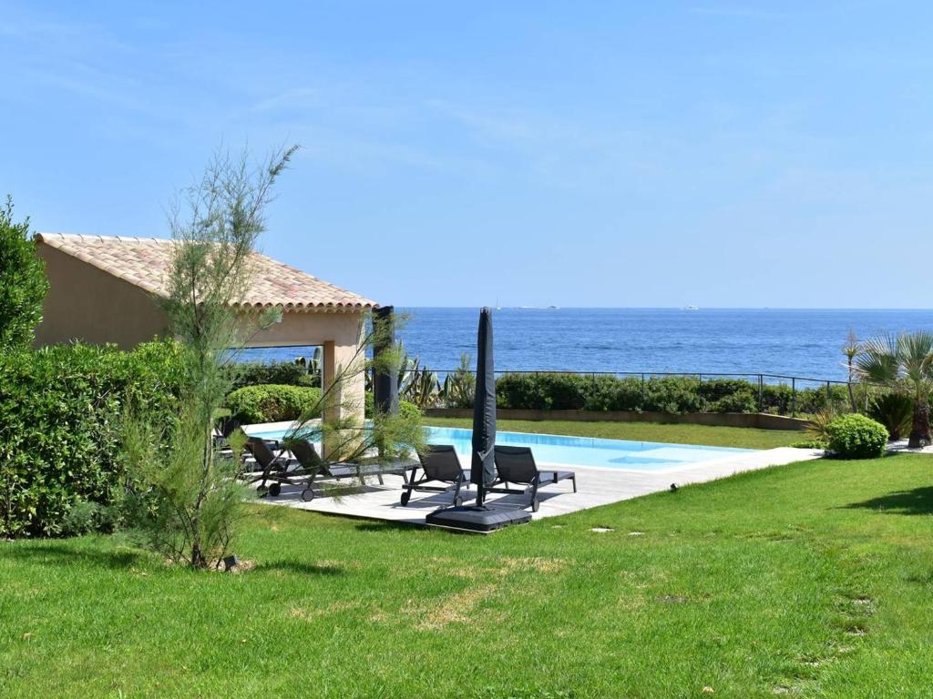 a yard with chairs and a swimming pool next to the ocean at Villa Les Issambres, 6 pièces, 10 personnes - FR-1-768-27 in Les Issambres