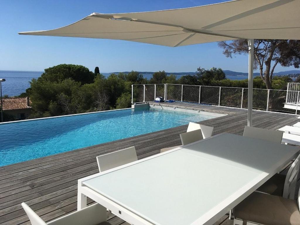 uma piscina com uma mesa e um guarda-sol em Villa Les Issambres, 5 pièces, 8 personnes - FR-1-768-37 em Les Issambres