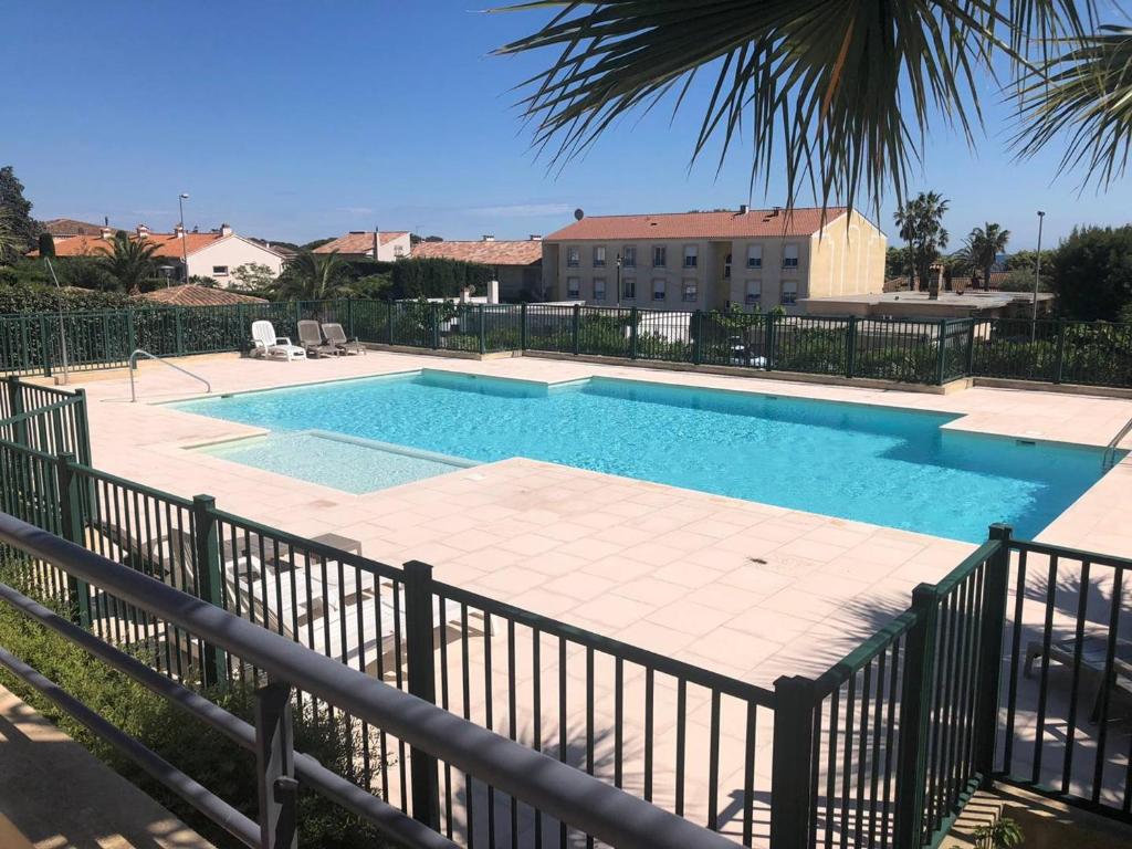 une piscine à côté d'une clôture métallique dans l'établissement T2 standing, piscine, clim, proche plage, parking, animaux OK - FR-1-768-47, aux Issambres