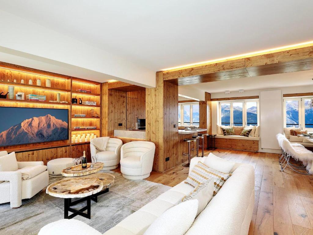 Il comprend un salon doté d'un mobilier blanc et de murs en bois. dans l'établissement Appartement duplex à Courchevel 1850 - 6 pers, 3 chambres, centre station - FR-1-564-116, à Courchevel