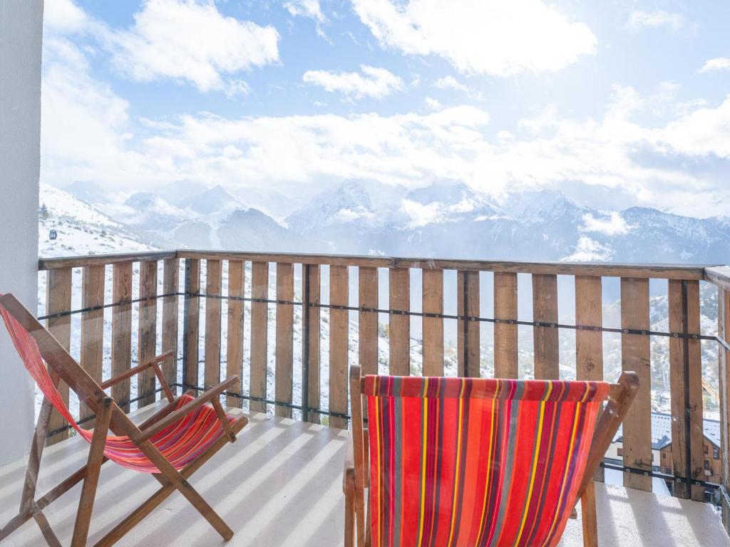 une terrasse avec deux chaises et une vue sur les montagnes dans l'établissement Appartement rénové avec balcon | WIFI | Casier à skis - FR-1-645-50, à Huez