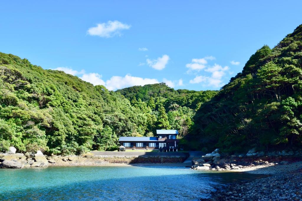 a building on the side of a river with trees at 佐世保VILLA青鹿Ur1 in Sasebo