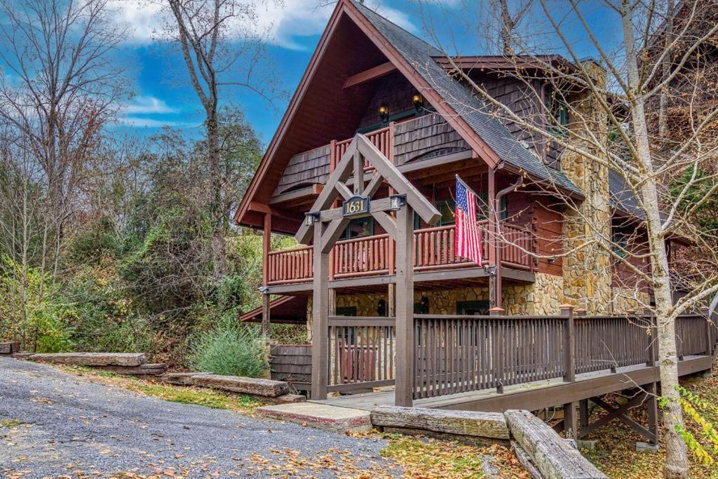 a large log cabin with an american flag on it at Bridgewood Cabin- New Listing - Hot Tub, Pool Table, Free Attraction Tickets in Pigeon Forge