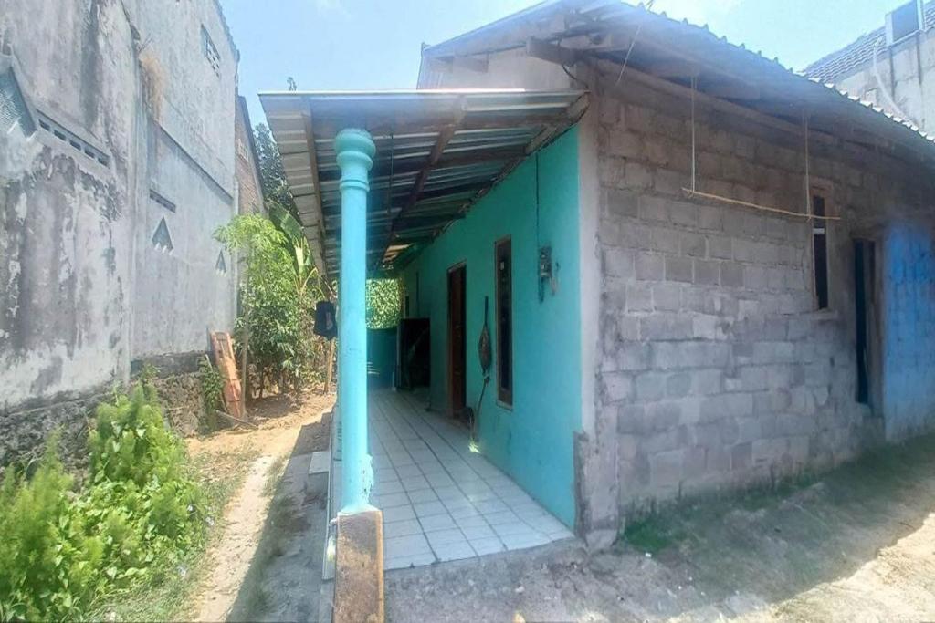 ein Gebäude mit einer blauen Tür und einer Stange in der Unterkunft SPOT ON 93324 Hadi Homestay Syariah in Sleman