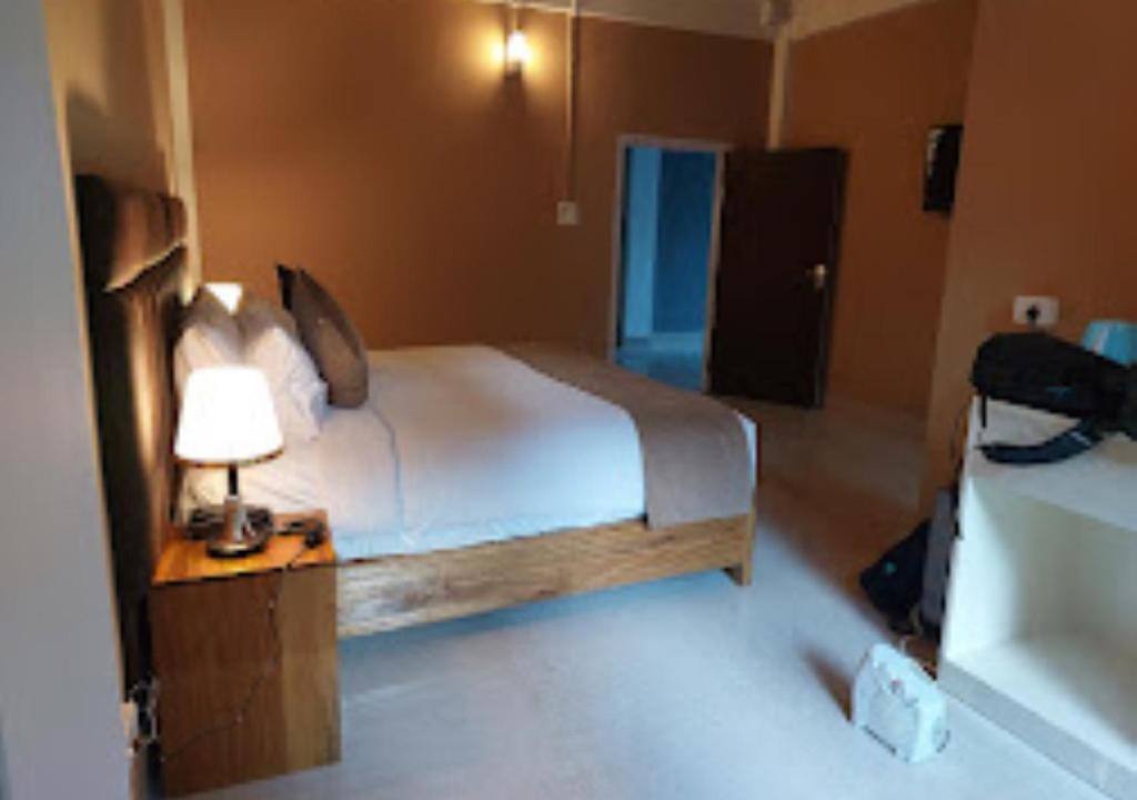 ein Schlafzimmer mit einem Bett und einer Lampe auf einem Tisch in der Unterkunft La Colline Resort Nagaland in Kohīma