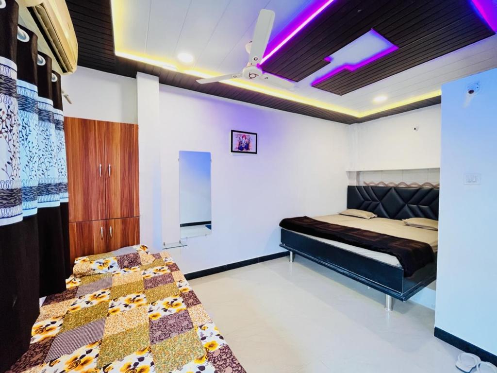 PALLAV GUEST HOUSE في اوجاين: غرفة نوم بسريرين مع اضاءة ارجوانية على الاسقف