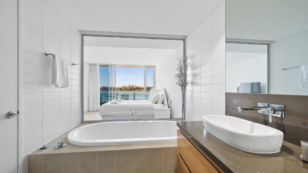 a bathroom with a tub and a sink and a mirror at Seapoint 102 in Mandurah