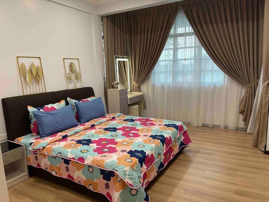 um quarto com uma cama grande e um edredão colorido em Welcome to Sarmax Homestay em Kuching