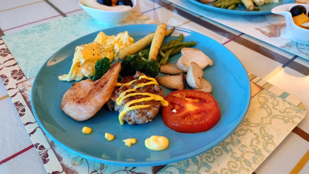 a blue plate of food with sausage and vegetables at Bestime B&amp;B in Jiji
