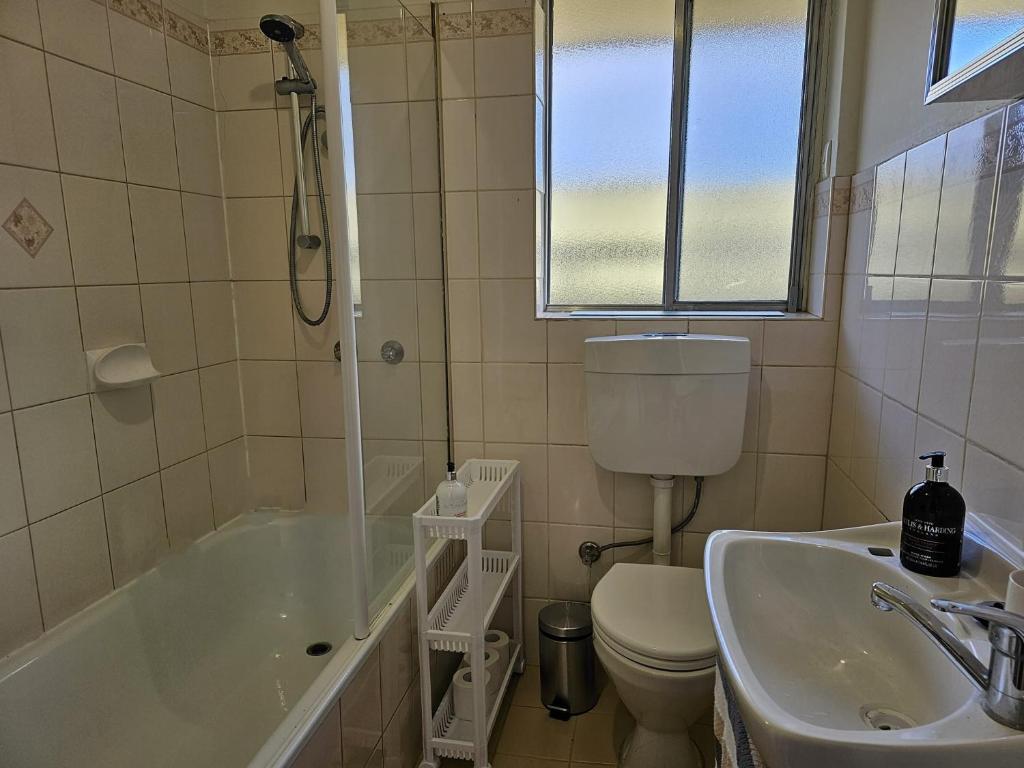 a bathroom with a tub and a toilet and a sink at Family Oasis in Adelaide in Bowden