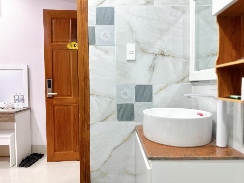 a white bathroom with a sink and a tub at Milan Homestay - Milanesa Hotel and Apartment in Vung Tau