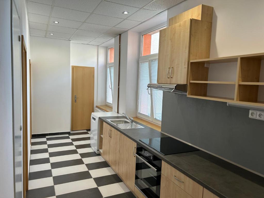 uma cozinha com um balcão preto e um piso xadrez em Apartmánový byt em Valašské Meziříčí