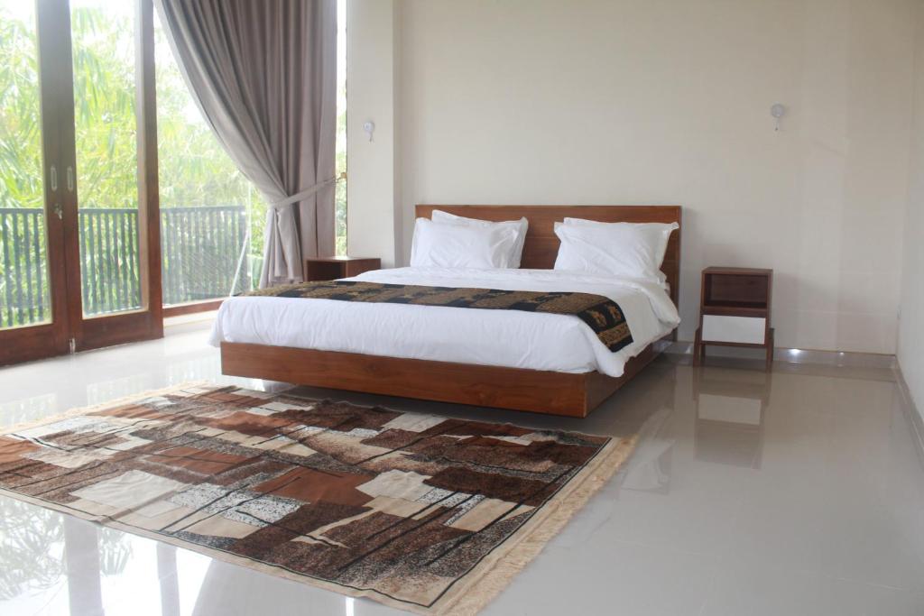 a bedroom with a bed and a large window at L'JAVAS VILLAS in Kalibendo