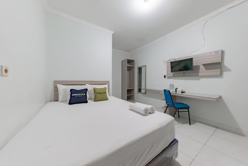 Habitación blanca con cama grande y escritorio. en Urbanview Hotel Sunday Cirebon by RedDoorz, en Cirebon