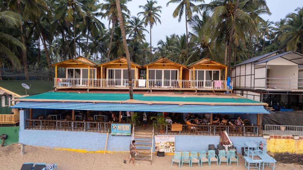 ein Restaurant am Strand mit Palmen im Hintergrund in der Unterkunft Hitide Beach Resort in Palolem