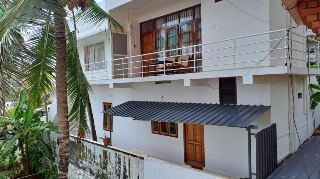 a white house with a balcony and a palm tree at VARMA SEA VIEW VILLAS in Trivandrum