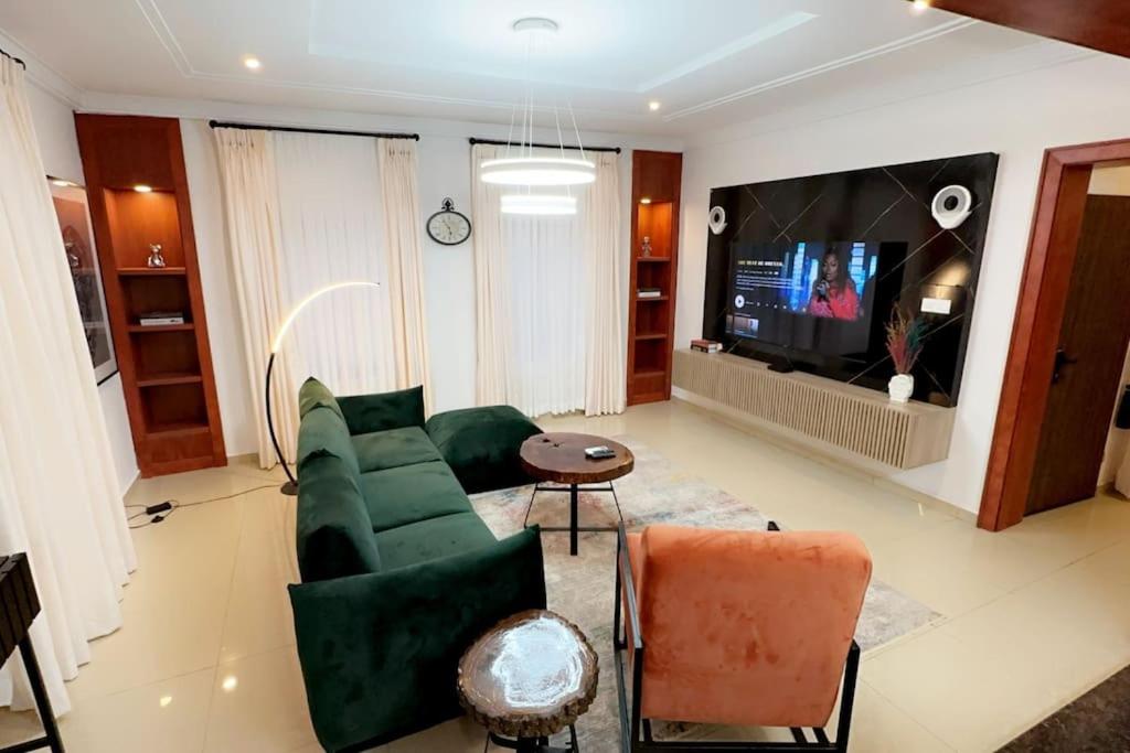 sala de estar con sofá verde y TV en Prive Apartments Katampe Extension 3bed, en Abuja