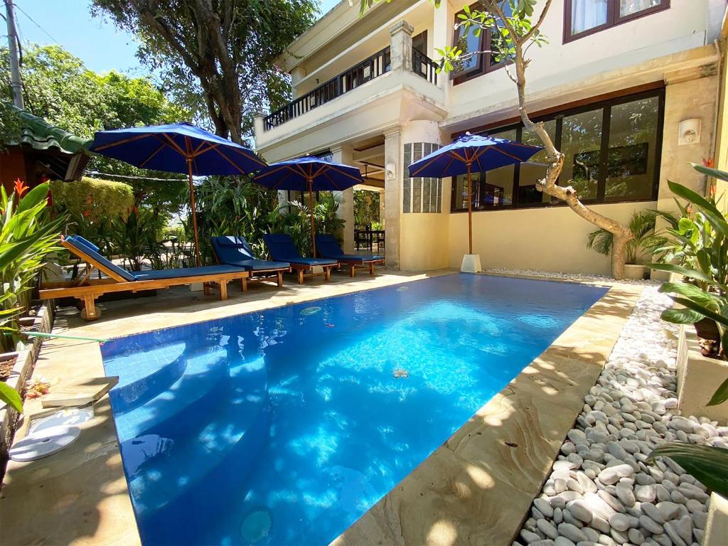 una piscina con ombrelloni di fronte a una casa di Bali Emerald Apartments a Sanur