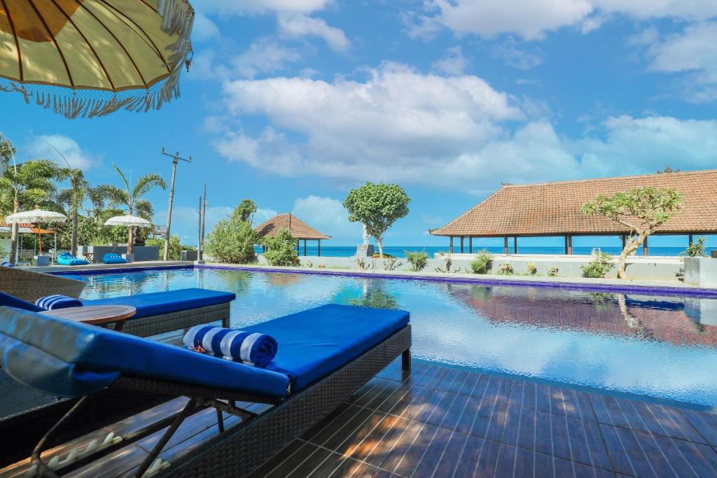- Piscina en el complejo con sillas azules y sombrilla en Grand Ball Beach Garden, en Nusa Penida