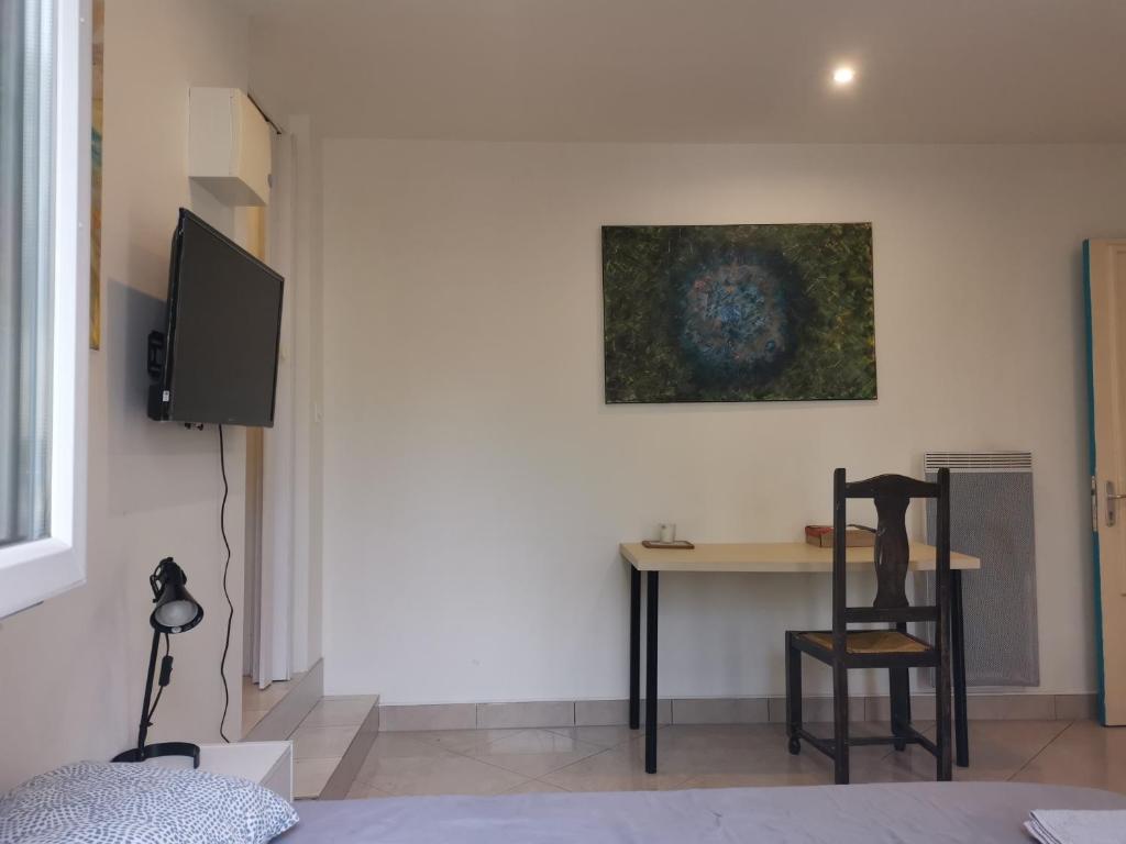 Habitación con mesa, TV y silla. en Cosy studio pour deux personnes, en Vitry-sur-Seine
