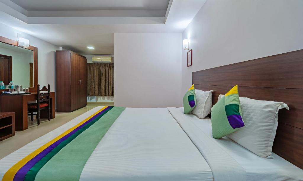 a bedroom with a large white bed with colorful pillows at Treebo Trend Central in Trichūr