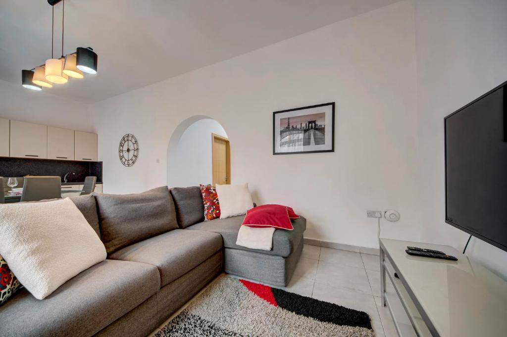 ein Wohnzimmer mit einem Sofa und einem TV in der Unterkunft St Julians apartment 1 in St Julian's