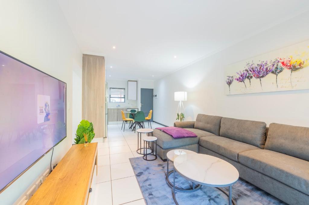 a living room with a couch and a tv at Luxury Home with an Office & Backup Power in Sandton