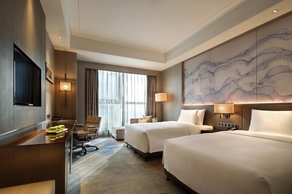 a hotel room with two beds and a desk at Wanda Realm Huangshi in Huangshi