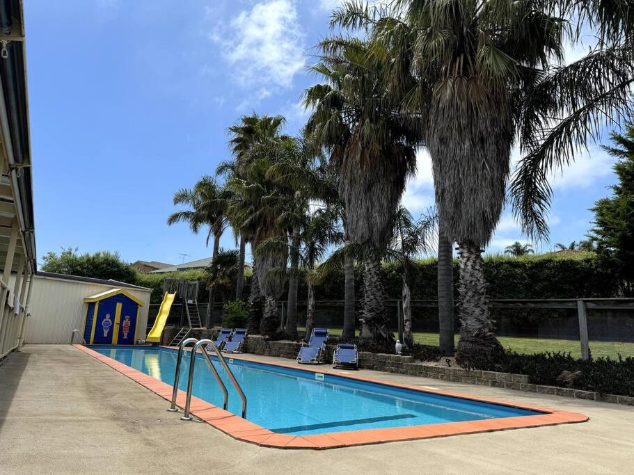 a swimming pool with a slide and palm trees at Relax, Resort Style in Rosebud