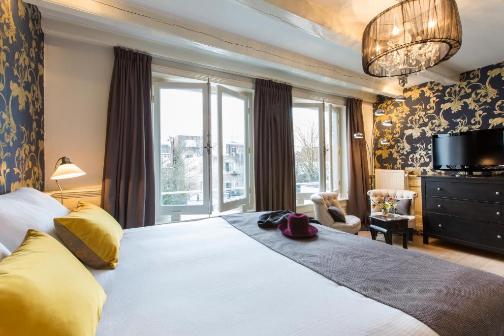 sypialnia z dużym łóżkiem i dużym oknem w obiekcie Grand Canal Boutique Hotel w Amsterdamie