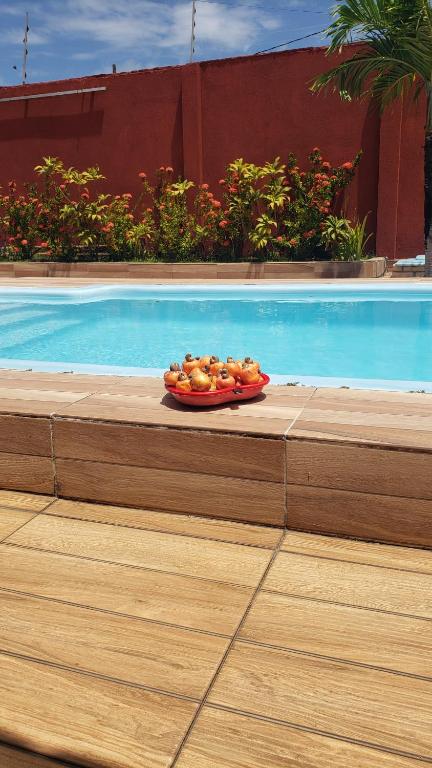 a plate of fruit sitting next to a swimming pool at Casanostra44 in Genipabu