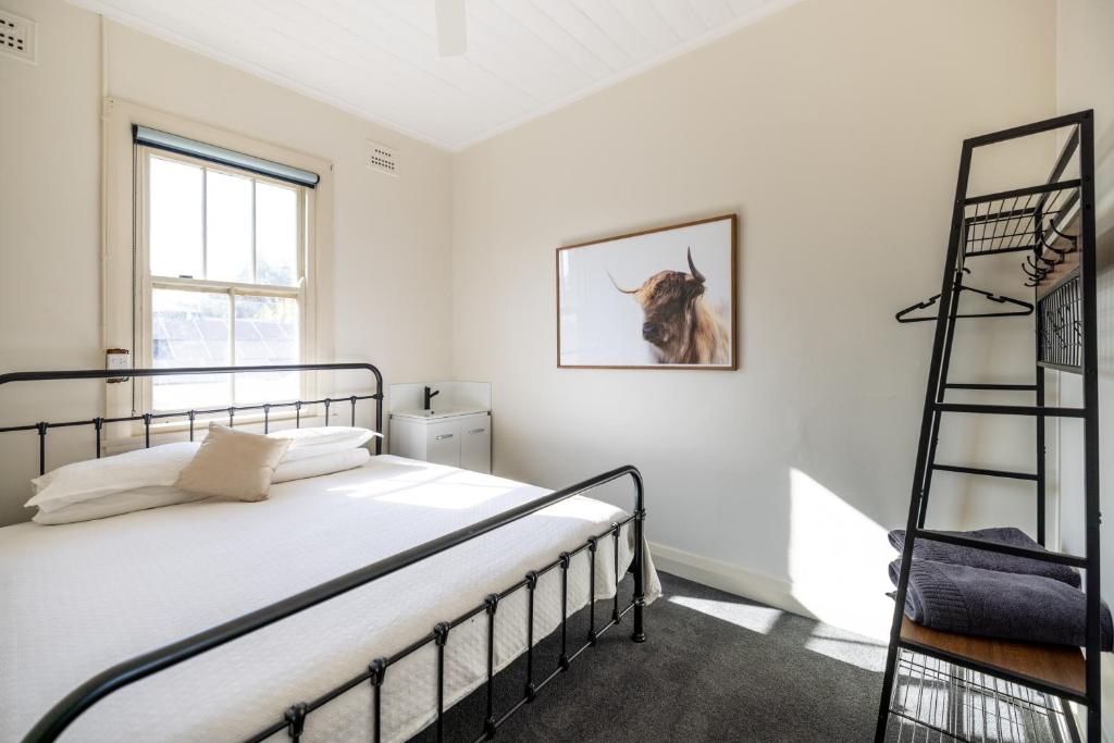 1 dormitorio con 1 cama y una foto de una vaca en la pared en The Middle en Adelong