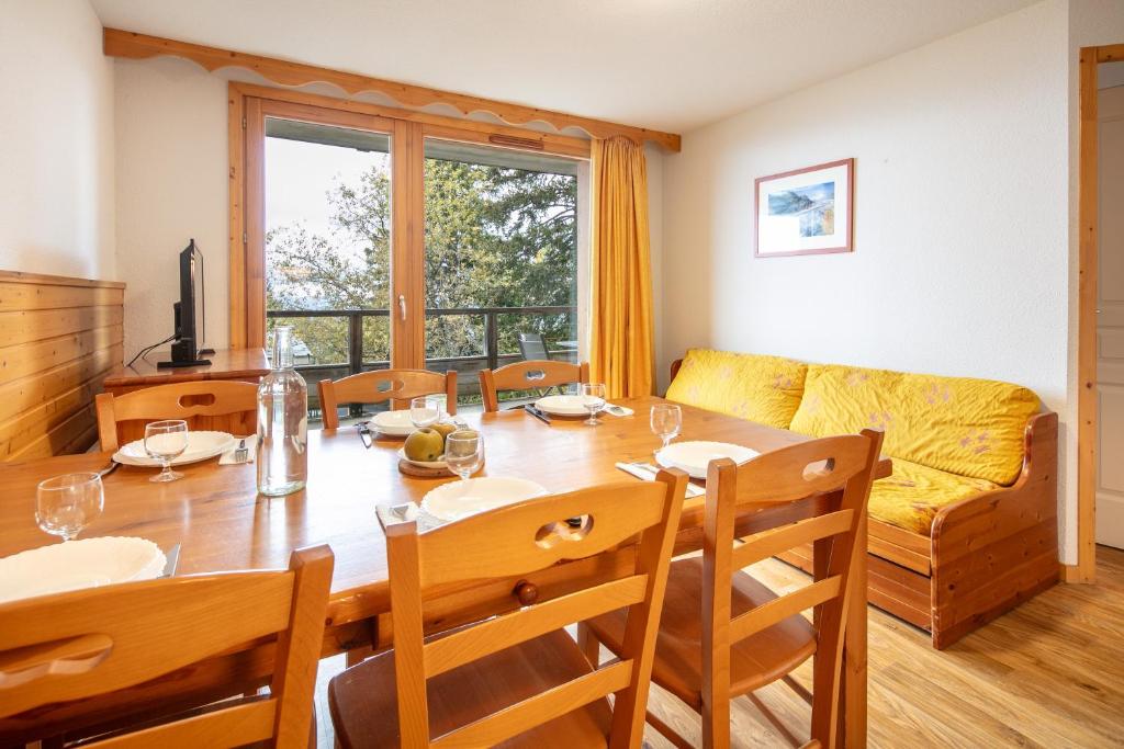 a dining room with a table and a couch at Le Chartreuse - Apt de charme in Chamrousse