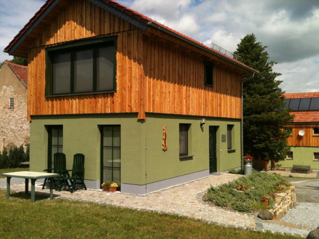 a green and wooden house with a table in front of it at Ferienhaus Sobetzko in Wilthen