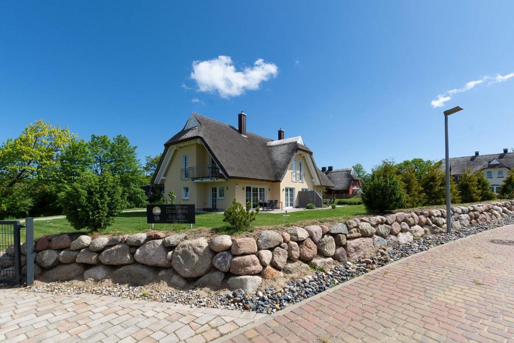 a stone retaining wall in front of a house at Strandvilla "Babette" - BALO B, direkt am Meer, mit Sauna in Lobbe