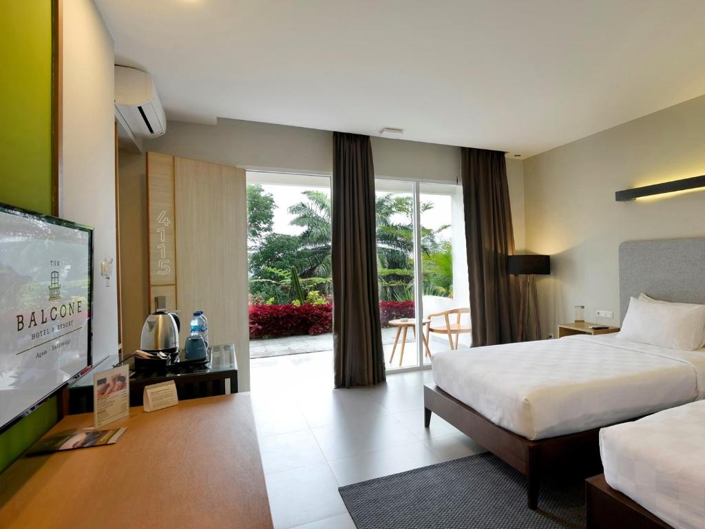 a hotel room with a bed and a flat screen tv at The Balcone Suites & Resort Powered by Archipelago in Bukittinggi