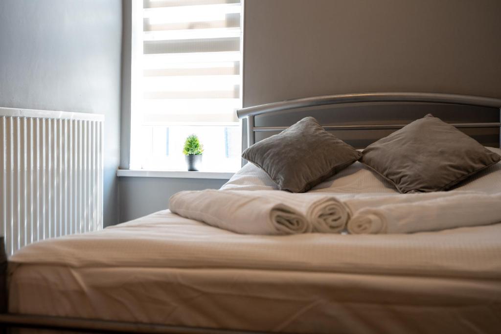 uma cama com lençóis e almofadas brancos e uma janela em Chatham house em Etruria