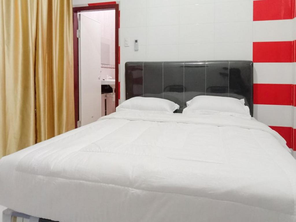 1 cama blanca grande con sábanas y almohadas blancas en Hotel 889 Syariah Redpartner Banda Aceh, en Banda Aceh