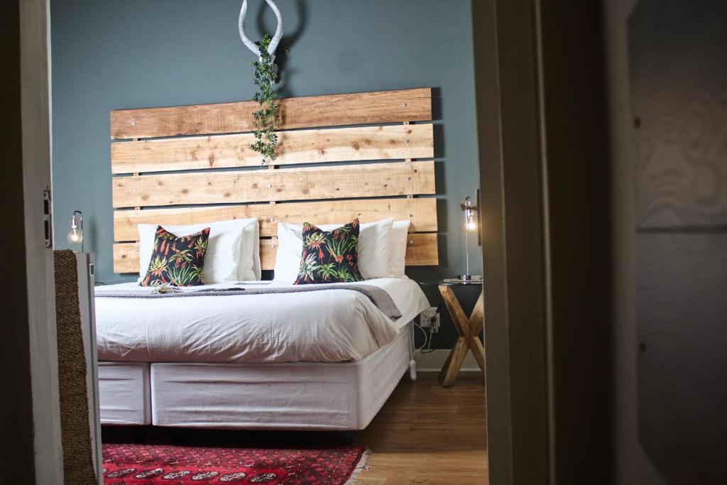 - une chambre avec un grand lit et une tête de lit en bois dans l'établissement De Akker Guest House Oudtshoorn, à Oudtshoorn