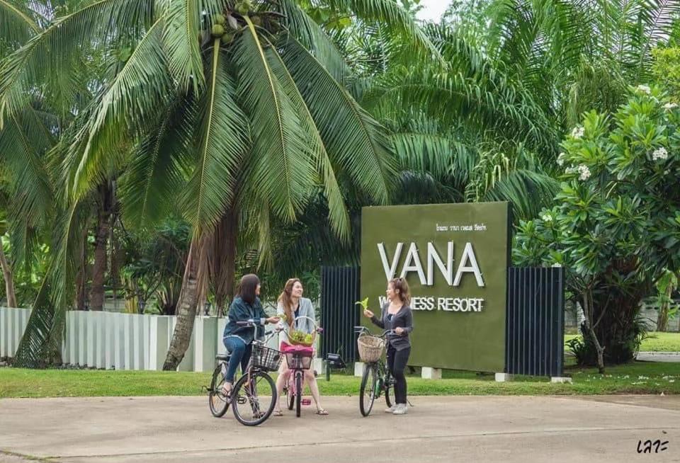 Tres mujeres montando sus bicicletas delante de un cartel en VANA Wellness Resort, 