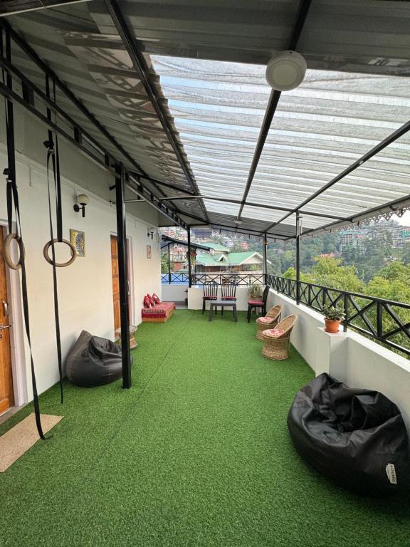 Habitación con alfombra verde y balcón con mesa y sillas. en Addy's Inn en Gangtok