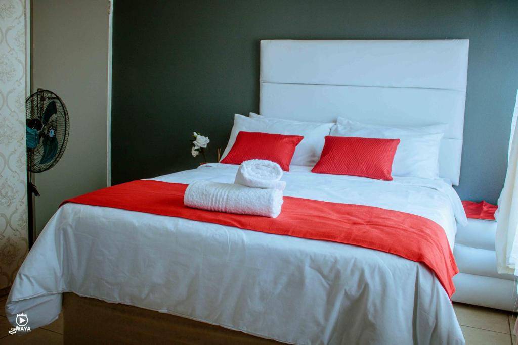 a white bed with red pillows and a red blanket at BARAKA mtata ! in Mthatha