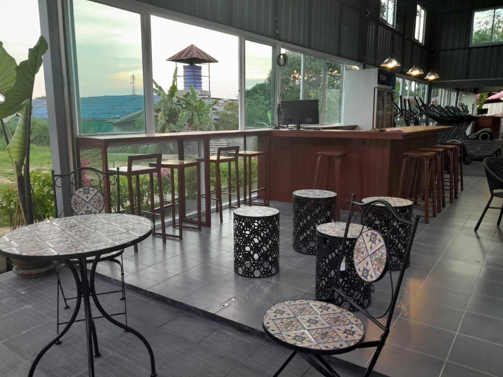 un restaurante con mesas y sillas y un bar en Thaineth Sport Camp, en Nong Prue