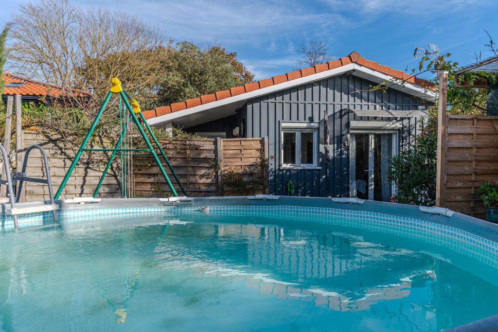 a swimming pool with a swing in front of a house at Chalet studio bassin d'arcachon in La Teste-de-Buch