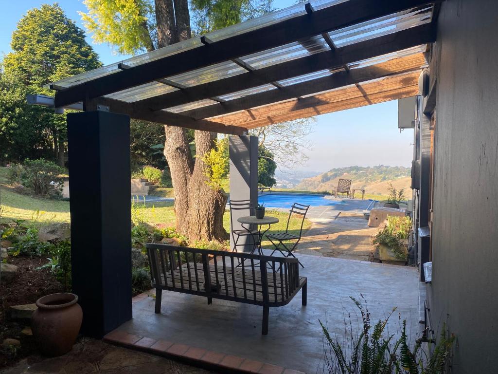 een bankje op een patio met uitzicht op een rivier bij Churchill Cottage in Gillitts